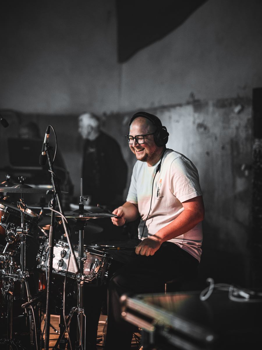 Schlagzeuger mit Kopfhörern lacht am Drumset, Schwarzweißfoto