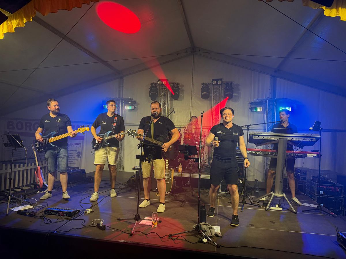 Die ganze Band auf der Bühne im Festzelt in rot-blauem Licht: Gitarren, Bass, Gesang und Keyboard